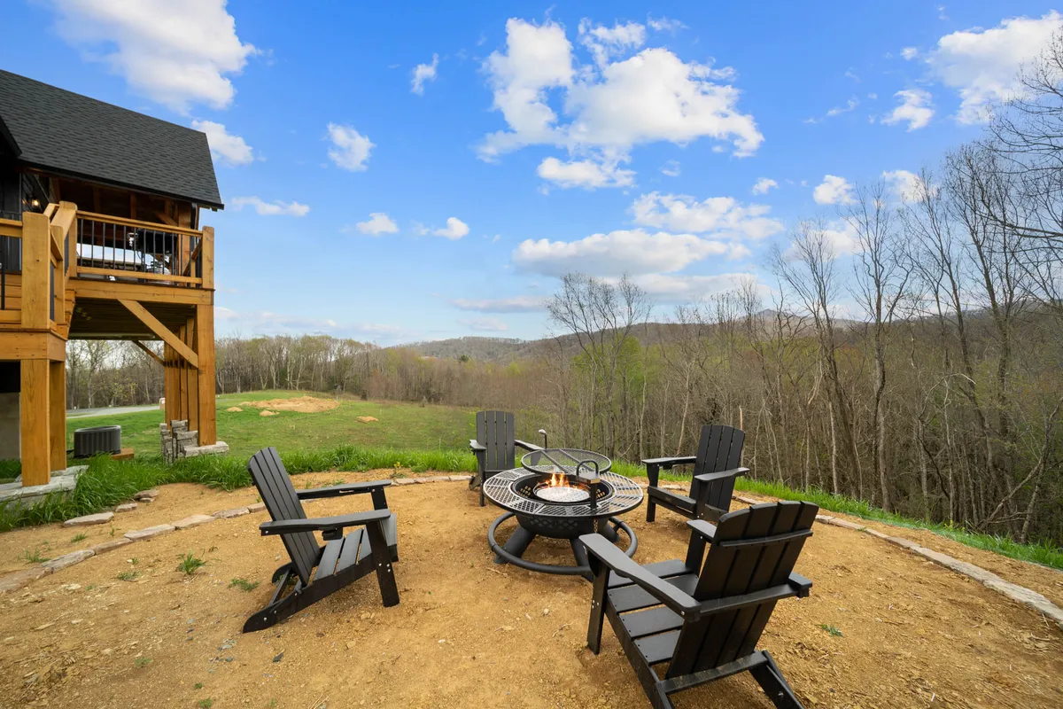 This image captures an inviting outdoor fire pit surrounded by chairs, set in a natural landscape. The setup is ideal for gatherings, with ample space for a family to sit together and enjoy activities like roasting s'mores or sharing stories under an open sky.