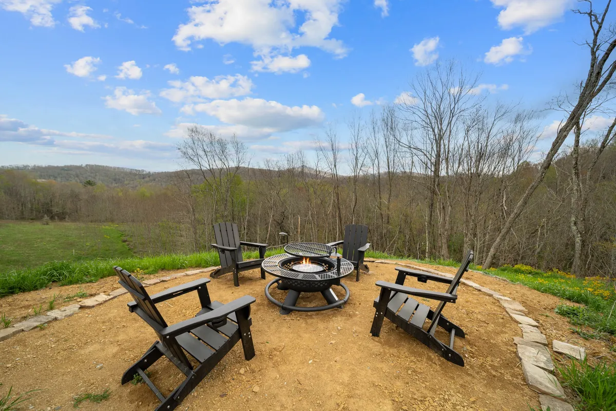 An inviting fire pit area with Adirondack chairs is set against a scenic mountain backdrop. The space is designed for gatherings, storytelling, and cozy evenings under the stars, capturing the communal and relaxing spirit of the property.