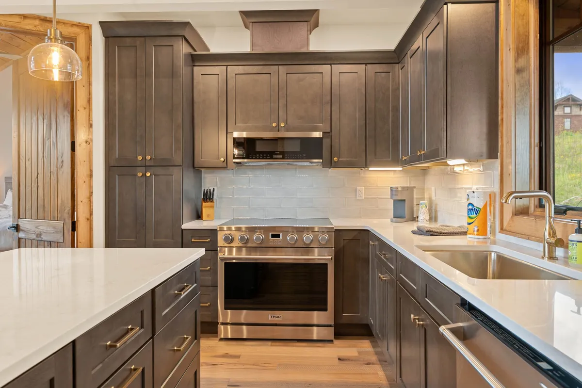 A welcoming kitchen interior with sleek dark cabinetry, a modern stainless steel oven, and a clean countertop. The space is arranged for both cooking and entertaining, and the overall aesthetic is modern yet cozy, supporting a range of culinary experiences.